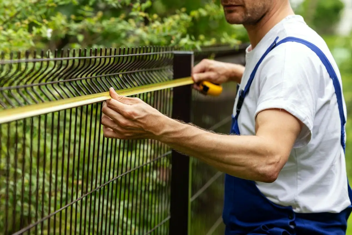 worker taking measurements with measuring tape for new fence