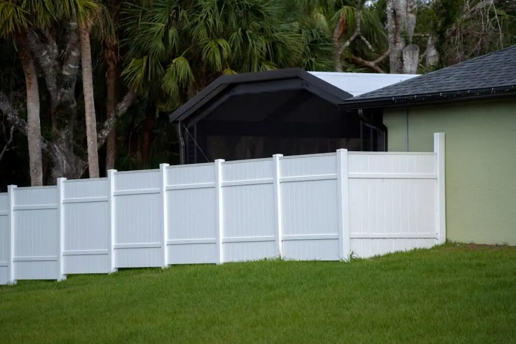 White vinyl picket fence on green lawn