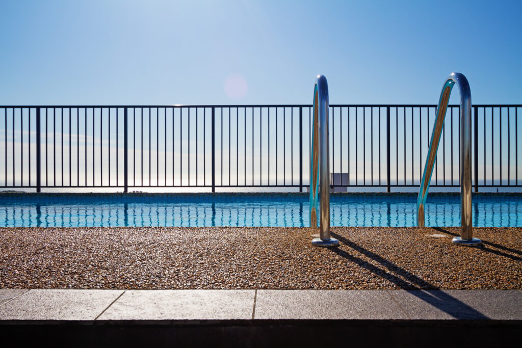 aluminum pool fence Swimming pool edge with ladder, fence and sky background
