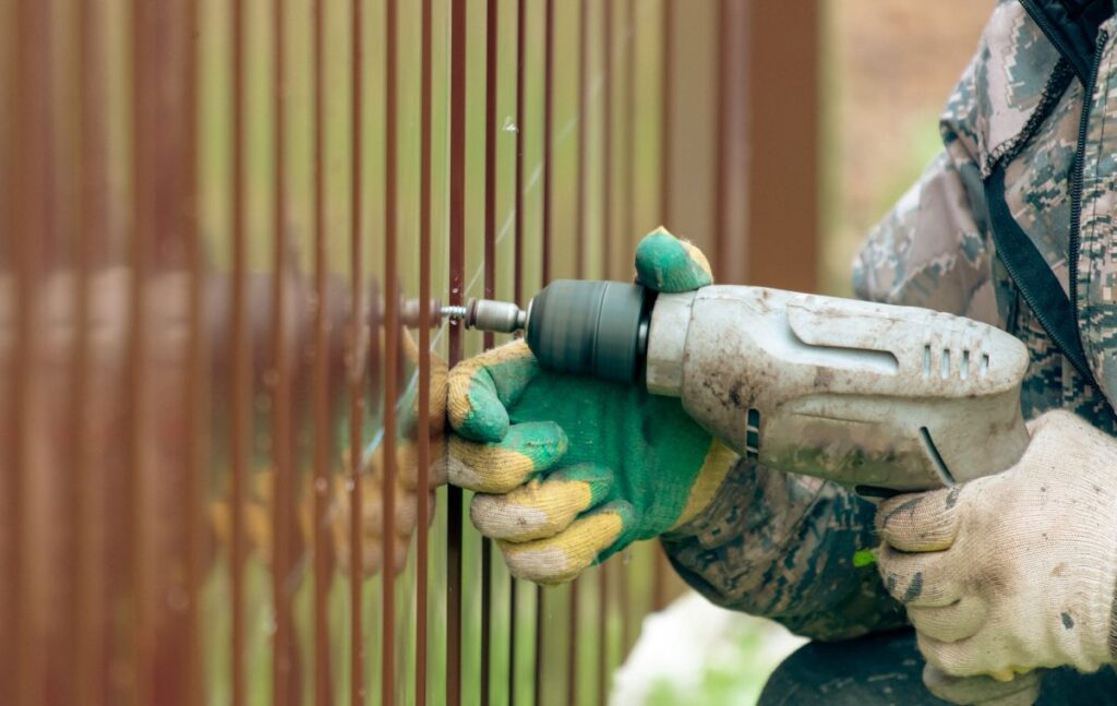 aluminum fence installation metallic fence worker using electric screwdriver