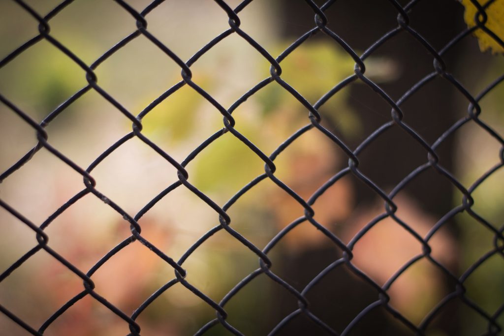 residential black chain link fence Installed metal fence, a fence from the grid separates the green zone. Background