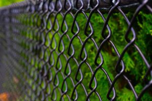 vinyl coated chain link fence A black chain link fence photographed from a creative perspective to give the image depth.