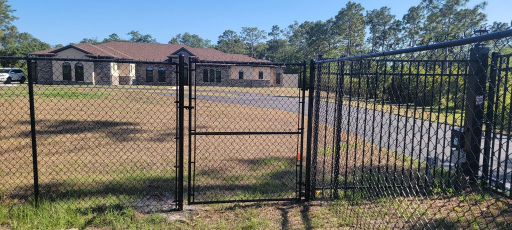 residential black chain link fence big shingle house on the back 