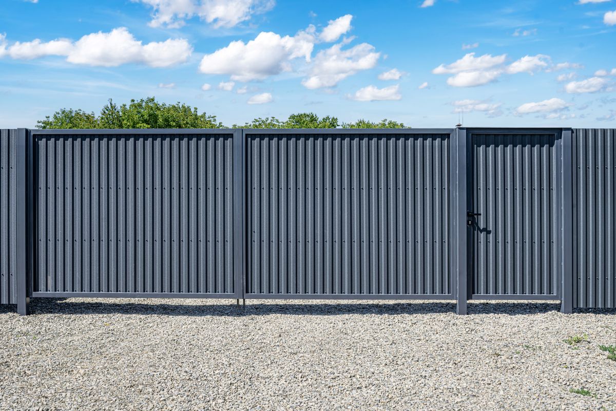 A modern gray corrugated metal fence with a built-in pedestrian gate