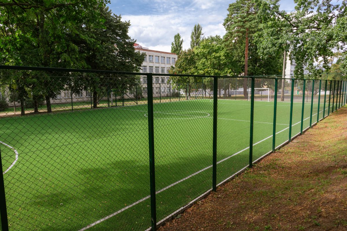 Closed school soccer field. Empty soccer stadium behind the fence
