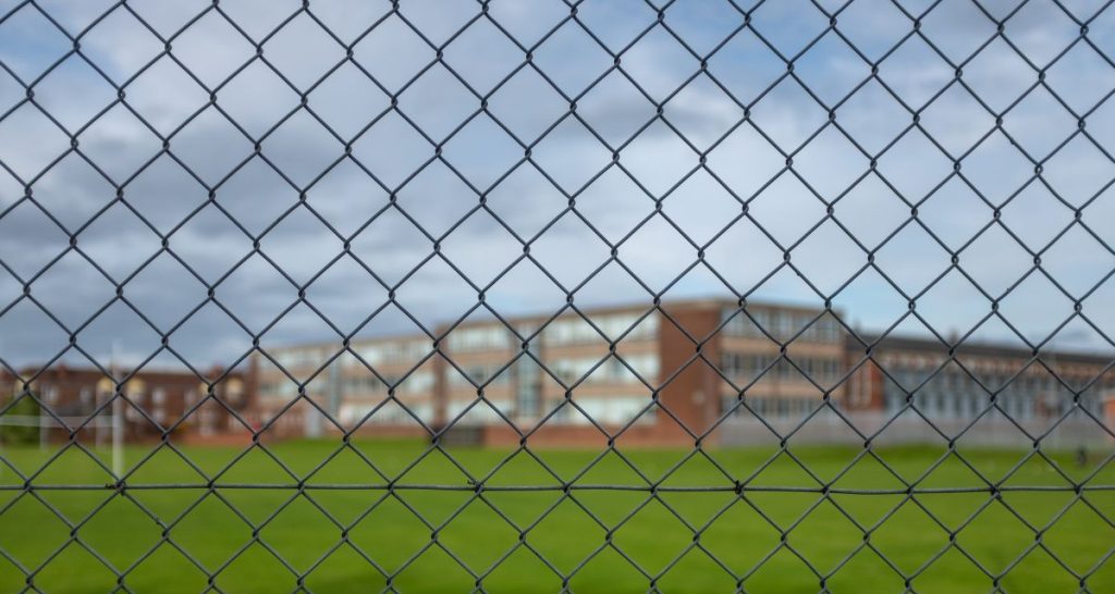 High School Building Behind A Fence