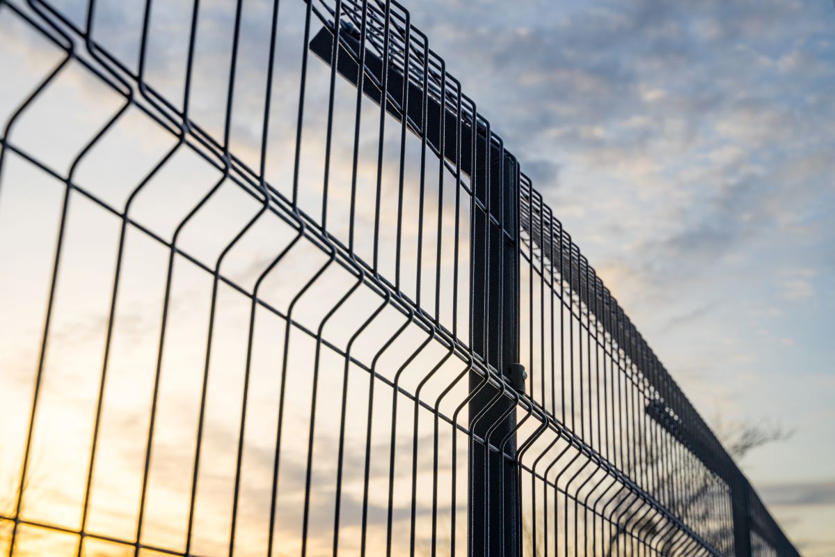 Steel grating fence made with wire on blue sky background. Sectional fencing installation
