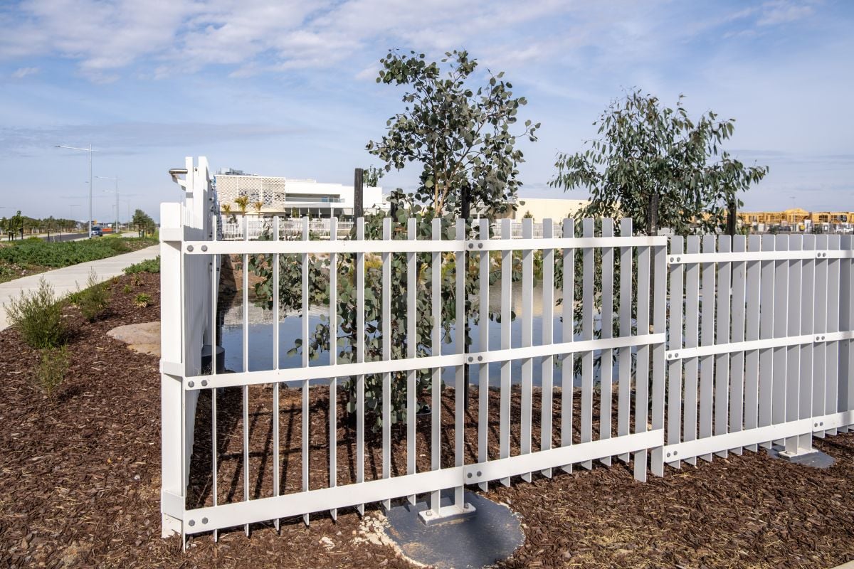 White metal pool safety fence beside a stormwater retention pond 